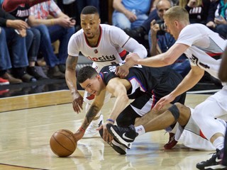 Hráč tímu LA Clippers J.J. Redick (v strede) sa naťahuje za loptou. Z oboch strán pribiehajú súperi z tímu Portlandu.