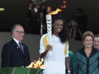 Brazílska volejbalistka Fabiana Claudinová (uprostred) drží horiacu olympijskú pochodeň.