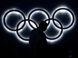 Divák na štadióne Maracana kráča popred osvetlený symbol piatich olympijských kruhov.