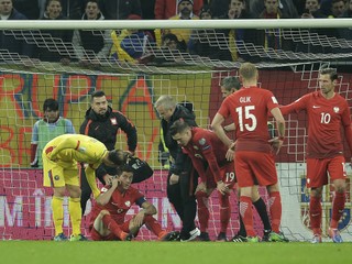 Robert Lewandowski sedí otrasený na zemi po tom, ako v jeho blízkosti vybuchol delobuch.