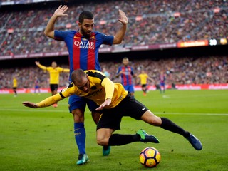 Po súboji s Ardom Turanom z Barcelony padá na trávnik Mikel Villanueva (v žlto-čiernom) z Málagy.