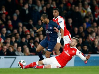 Aaron Ramsey z Arsenalu (vpravo) posiela sklzom k zemi hráča PSG Lucasa.