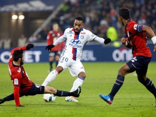 Alexandre Lacazette (v strede) z Lyonu sa pokúša presadiť cez dvoch brániacich futbalistov súpera.