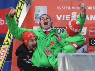 Kolegovia z nemeckého tímu Markus Eisenbichler (vľavo) a Richard Freitag (vpravo) oslavujú s Andreasom Wellingerom jeho triumf.