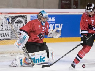 Obranca Banskej Bystrice Branislav Kubka odpaľuje puk pred spoluhráčom - brankárom Teemuom Lassilom.