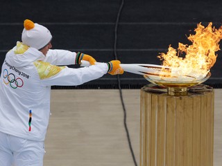 Grécky slalomár Ioannis Proios zapaľuje olympijskú pochodeň počas jej slávnostného odovzdávania kórejským organizátorom ZOH 2018 v Pjongčangu na aténskom štadióne Panathinaikon  31. októbra 2017.
