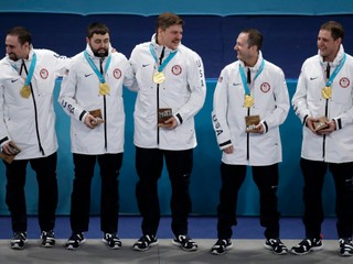 Americkí reprezentanti v curlingu zľava Joe Polo, John Landsteiner, Matt Hamilton, Tyler George a John Shuster oslavujú na pódiu víťazstvo a zisk zlatej medaily.