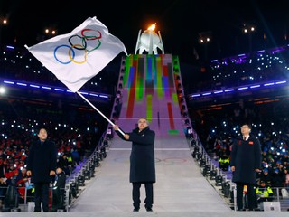 Prezident Medzinárodného olympijského výboru (MOV) Thomas Bach (uprostred) máva olympijskou zástavou počas záverečného ceremoniálu na ZOH 2018.