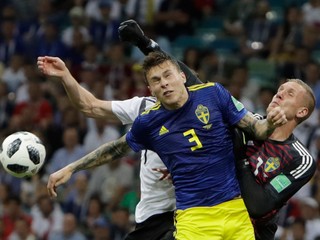 Švédsky brankár Robin Olsen boxuje loptu v súboji s Nemcom Julianom Draxlerom, ktorého bráni Victor Lindelöf.