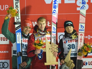Ruský skokan Jevgenij Klimov (v strede) oslavuje na pódiu víťazstvo. Na druhom mieste skončil Nemec Stephan Leyhe (vľavo) a na treťom Japonec Rjoju Kobajaši (vpravo).