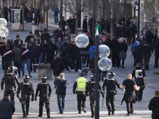 Policajti usmerňujú skupinu fanúšikov.