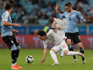 Kodži Mijoši v bielom drese Japonska strelil Uruguaju dva góly. Bráni ho Rodrigo Bentancur.