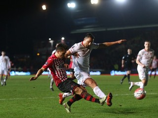 O loptu bojujú hráč tímu Exeter City Tom Nichols (vľavo) a Jose Enrique z Liverpoolu.