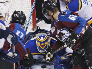 Brankár St.Louis Blues Brian Elliott kryje puk pred dobiedzajúcimi hráčmi domáceho Colorada.