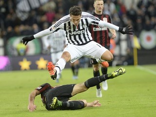Juraj Kucka z AC Miláno (vľavo) posiela sklzom k zemi Hernanesa z Juventusu.