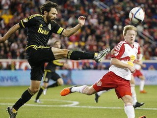 Skúsený Michael Parkhurst odkopáva loptu pred Daxom McCarthym z New Yorku Red Bulls.