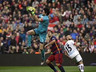 Brankár Deportiva La Coruňa Dario Lux chytá loptu vo výskoku pred Luisom Suárezom.