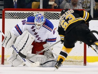 Hokejista Bostonu Bruins Brad Marchand skóruje pomedzi betóny brankára New Yorku Rangers Jeffa Malcolma.