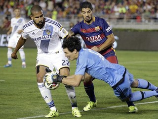 Brankár Los Angeles Galaxy Brian Rowe chytá loptu pred dobiedzajúcim Luisom Suárezom z Barcelony. Situáciu kontroluje jeho spoluhráč Leonardo (s číslom 22).
