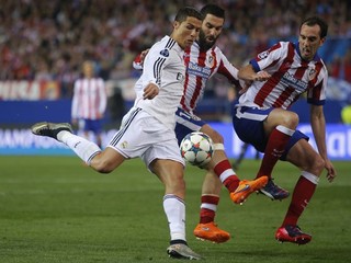 Cristiano Ronaldo (v bielom) sa dostáva do zakončenia. Zblokovať jeho pokus sa snaží dvojica hráčov Atlética - Diego Godín (vpravo) a Arda Turan.