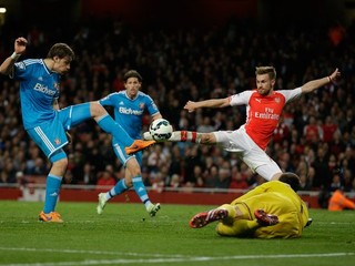 Futbalista Arsenalu Aaron Ramsey (v červenom drese) sa snaží zakončiť pred ležiacim brankárom Sunderlandu Costelom Pantilimonom. Bráni ho Sebastian Coates (vľavo).