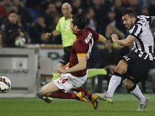 Carlos Tévez z Juventusu (vpravo) bojuje o loptu s hráčom AS Rím Kostasom Manolasom.