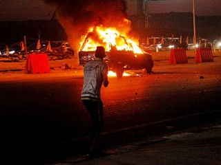 Horiace auto a zdevastované ulice po nepokojoch pred futbalovým zápasom.