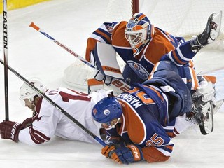 Hráč Arizony Coyotes Joe Vitale (14) a Slovák Martin Marinčin z Edmontonu Oilers (85) padajú na brankára Edmontonu Bena Scrivensa (30) v tretej tretine prípravného zápasu NHL v Edmontone 1. októbra.