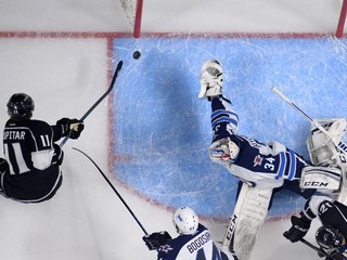 Center Los Angeles Kings Anže Kopitar (vľavo) strieľa gól brankárovi Michaelovi Hutchinsonovi z Winnipegu Jets, vpravo sa pozerá Marián Gáborík, 12. októbra.
