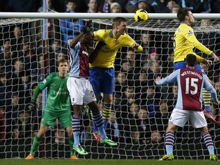 Christain Benteke z Aston Villy (vľavo). Blokuje ho Per Mertesacker z Arsenalu.