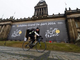 Cyklista prechádza okolo veľkého banneru k Tour 2014 na budove mestskej radnice v Leedsi.