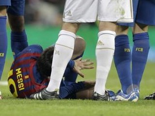 Lionel Messi leží na zemi po tom ako mu stúpil na ruku obranca Pepe.