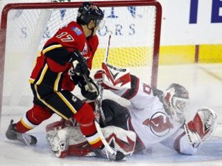 Brankár New Jersey Devils Martin Brodeur zrazený na ľad hráčom Calgary Flames Rene Bourquom.