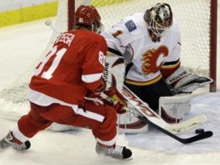 Brankár Calgary Flames Curtis McElhinney zasahuje pred Slovákom Marianom Hossom z Detroitu Red Wing.