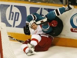 Ryan Clowe zo San Jose Sharks v tvrdom súboji s hráčom Detroitu Red Wings Niklasom Kronwallo, (v bielom).