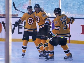 David Pastrňák, Brad Marchand a Patrice Bergeron sa tešia z gólu Bostonu Bruins pod holým nebom.