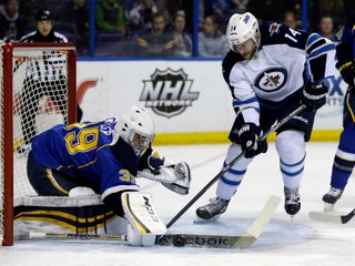 Anthony Peluso (vpravo) hral v NHL za Winnipeg, Washington a za Calgary. Na snímke v drese Jets proti brankárovi St. Louis Blues Ryanovi Millerovi.  