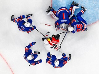 Austria's Peter Schneider, cen, and USA's goaltender Devin Cooley, top, challenge for the puck during the 2026 IIHF Men's Ice Hockey World Championship preliminary round group A match between United States and Austria in Zurich, Switzerland, Tuesday, May 26, 2026. (Andreas Becker/Keystone via AP)