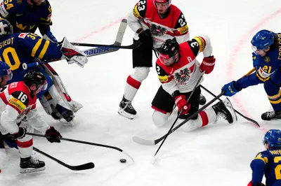 Players battle for the puck during the group A match between Sweden and Austria at the ice hockey world championship in Tampere, Finland, Sunday, May 14, 2023. (AP Photo/Pavel Golovkin)