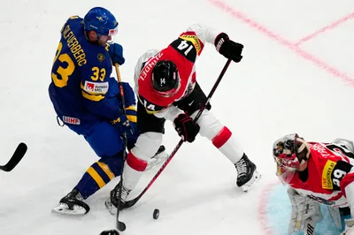 Sweden's Jakob Silfverberg, left, and Austria's Kilian Zundel battle for the puck during the group A match between Sweden and Austria at the ice hockey world championship in Tampere, Finland, Sunday, May 14, 2023. (AP Photo/Pavel Golovkin)