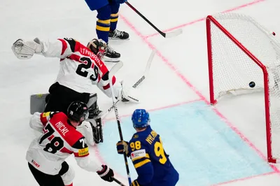 Sweden's Leo Carlsson, top, scores his side's fourth goal past Austria's goalie Bernhard Starkbaum during the group A match between Sweden and Austria at the ice hockey world championship in Tampere, Finland, Sunday, May 14, 2023. (AP Photo/Pavel Golovkin)