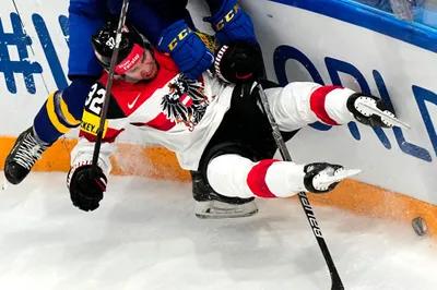 Austria's Bernd Wolf, right, and Sweden's Andre Petersson battle for the puck during the group A match between Sweden and Austria at the ice hockey world championship in Tampere, Finland, Sunday, May 14, 2023. (AP Photo/Pavel Golovkin)