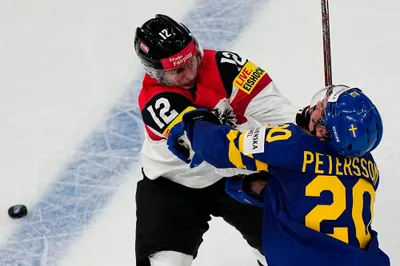 Sweden's Andre Petersson, right, and Austria's David Maier battle for the puck during the group A match between Sweden and Austria at the ice hockey world championship in Tampere, Finland, Sunday, May 14, 2023. (AP Photo/Pavel Golovkin)