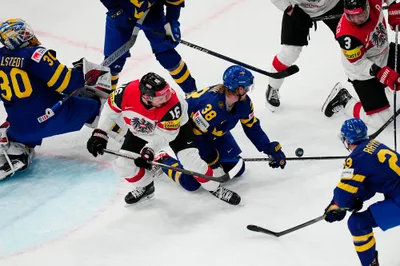 Players battle for the puck during the group A match between Sweden and Austria at the ice hockey world championship in Tampere, Finland, Sunday, May 14, 2023. (AP Photo/Pavel Golovkin)