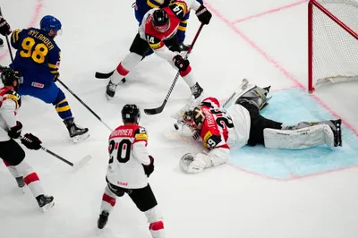 Austria's goalie Bernhard Starkbaum, right, tries to cover the puck during the group A match between Sweden and Austria at the ice hockey world championship in Tampere, Finland, Sunday, May 14, 2023. (AP Photo/Pavel Golovkin)