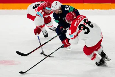 United States Rocco Grimaldi, centre, battles for the puck with Denmark's Morten Poulsen, right, and Mikkel Boedker during the group A match between United States and Denmark at the ice hockey world championship in Tampere, Finland, Saturday, May 20, 2023. (AP Photo/Pavel Golovkin)
