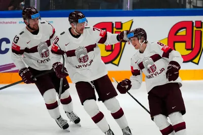 Latvia's Dans Locmelis (85), right, celebrates their goal with Miks Indrasis (70) and Rihards Bukarts (13) during the semifinal match against Canada at the Ice Hockey World Championship in Tampere, Finland, Saturday, May 27, 2023. (AP Photo/Pavel Golovkin)