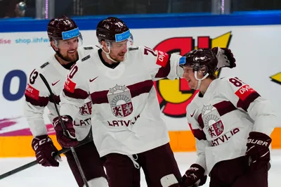 Latvia's Dans Locmelis (85), right, celebrates their goal with Miks Indrasis (70) and Rihards Bukarts (13) during the semifinal match against Canada at the Ice Hockey World Championship in Tampere, Finland, Saturday, May 27, 2023. (AP Photo/Pavel Golovkin)