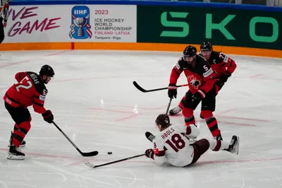 Canada's MacKenzie Weeger (52) tries to clear the puck against Latvia's Rodrigo Abols (18) during their semifinal match at the Ice Hockey World Championship in Tampere, Finland, Saturday, May 27, 2023. (AP Photo/Pavel Golovkin)