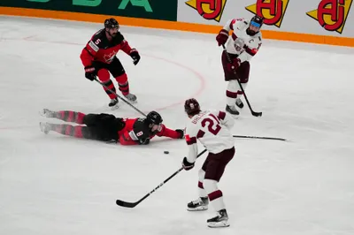 Canada's Cody Glass (8) falls to the ice between Latvia's Rudolfs Balcers (21) and Kaspars Daugavins (16) to defend the puck during their semifinal match at the Ice Hockey World Championship in Tampere, Finland, Saturday, May 27, 2023. (AP Photo/Pavel Golovkin)